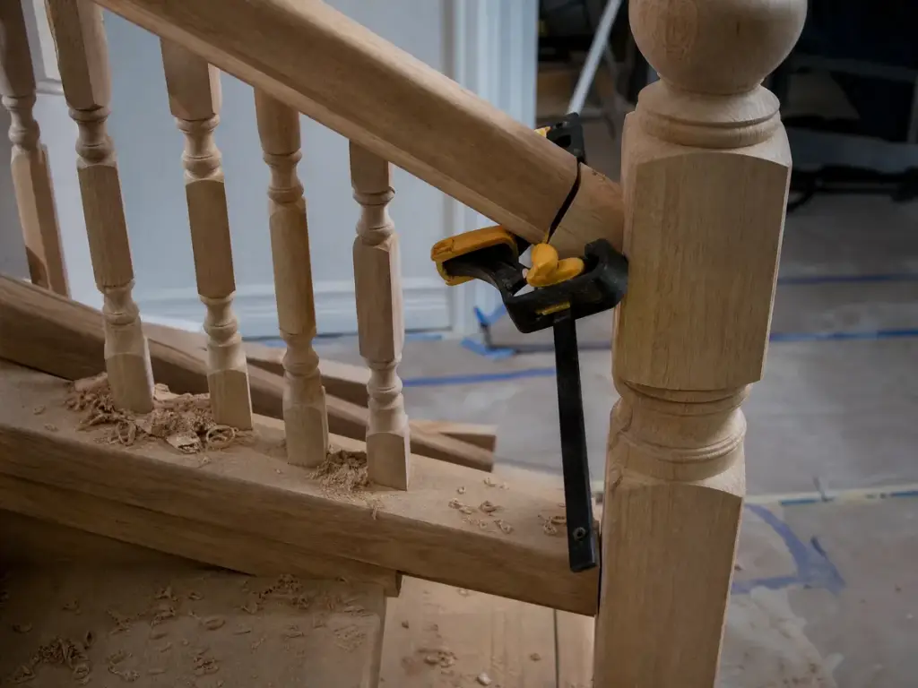 Newel post and balusters being fitted to a handrail with a clamp holding the joint