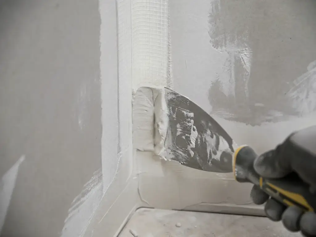 Paper tape being bedded into compound at an inside corner with a corner trowel