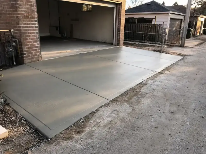 Freshly finished concrete garage slab and apron with control joints cut in