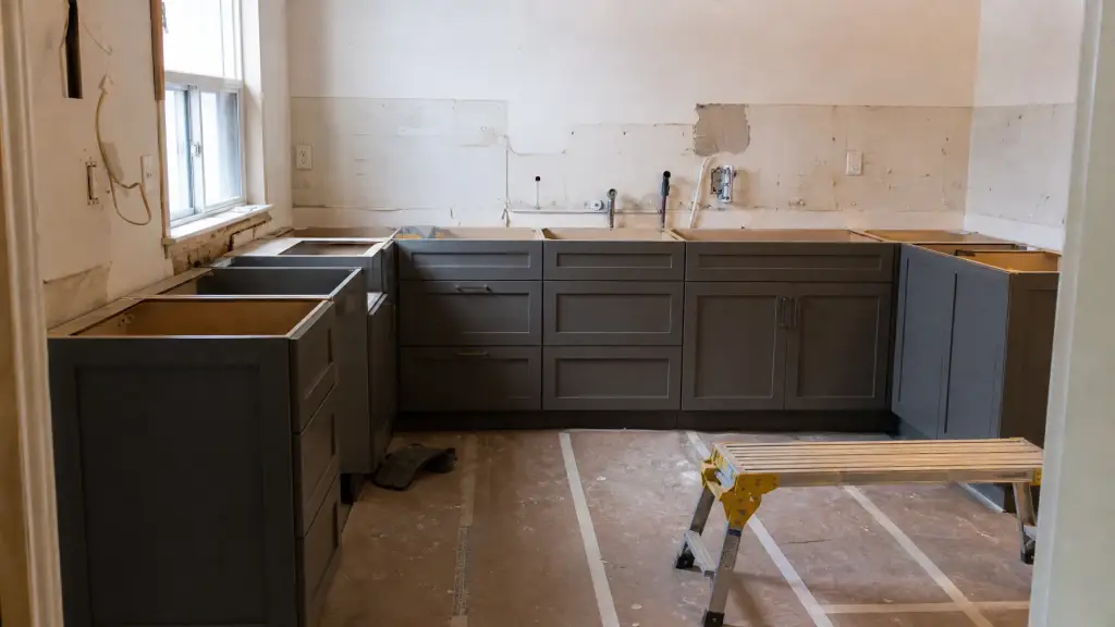 Kitchen mid renovation with base cabinets levelled and plumbing rough in visible at the wall