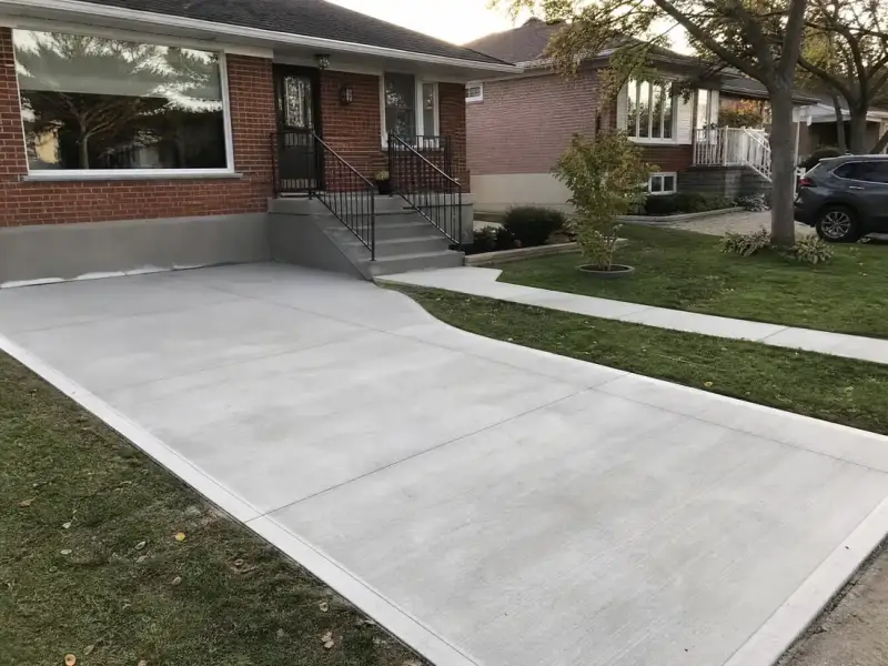Newly poured concrete driveway and walkway with clean control joints in front of a bungalow