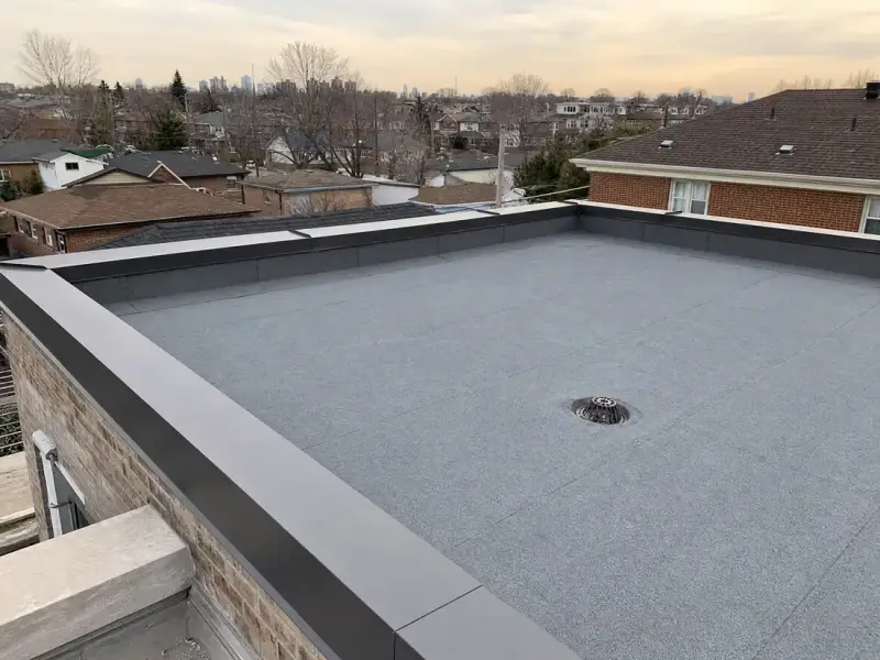 Completed flat roof with new membrane, neat seams, parapet flashing and a roof drain