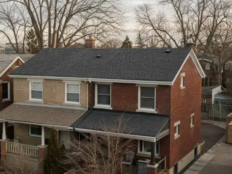 Completed asphalt shingle roof on a Toronto semi with a clean valley and new ridge cap