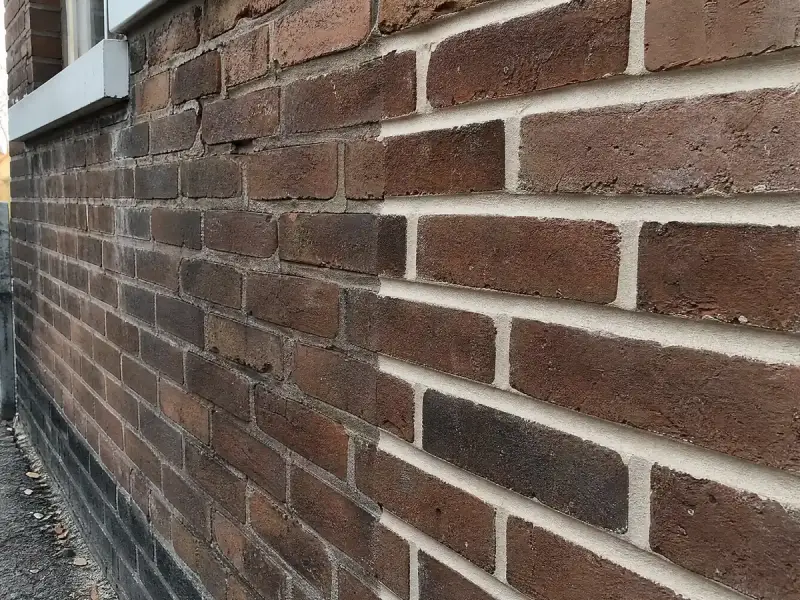 Brick wall with half the mortar joints freshly repointed and half still weathered